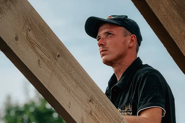 Zimmermann auf einem neuen Dachstuhl zwischen den Sparren